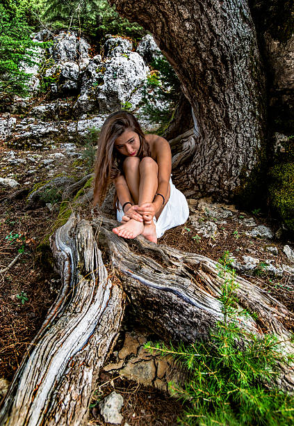 Young girl sitting in the forest alone