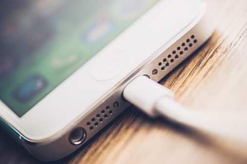 Suffolk, Virginia, USA - May 20, 2014: A horizontal shot of an Apple iPhone 5 being recharged via a connection cable. Shot in natural light.