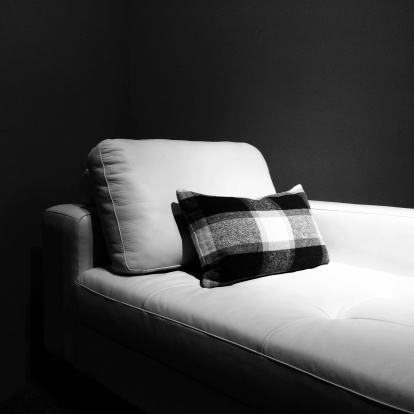 White leather couch in a dark room, under the light.