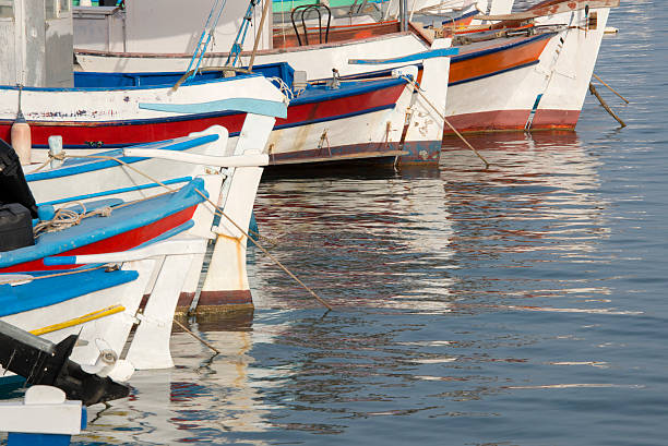 Traditional fishing boats painted in vivid colors docked in Setubal harbor, Portugal, on a calm summer afternoon in August 2025.