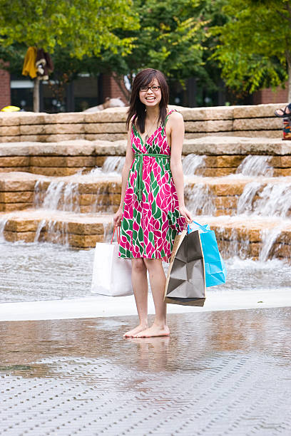 Cute Asian girl having fun in the fountain after a long day of shopping in the Pearl District, Portland Oregon.