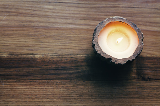 Overhead of a burning decorative candle on a wooden background