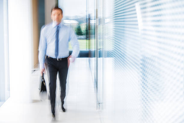 istock Businessman walking down a brighlty lit office corridor 492631410