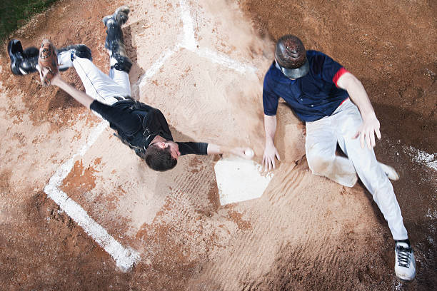 Baseball Player Sliding Into Home Base A top view of a baseball player sliding into home base while the catcher slides in as well trying to make the tag out. spring training stock pictures, royalty-free photos & images
