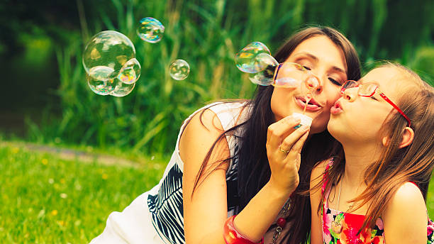 istock Mother and child blowing soap bubbles outdoor. 492641032
