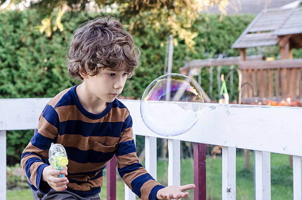 istock Little boy making soap bubble and trying to hold them 492642188
