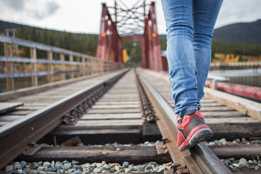Traveling woman walking on the railroad track. Focus on the shoes.