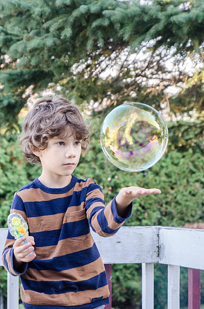 istock Little boy making soap bubble and trying to hold them 492642416