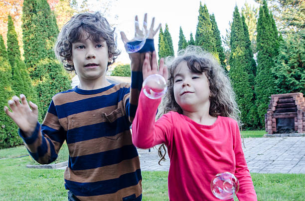 istock Two kids playing with soap bubble outside 492644060