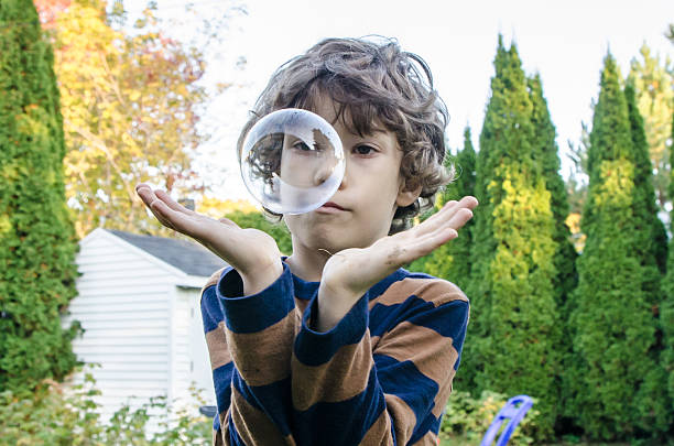 istock Little boy making soap bubble and trying to hold them 492644312