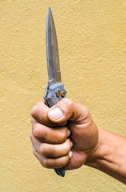 istock Hand holding a knife on yellow background 492644994