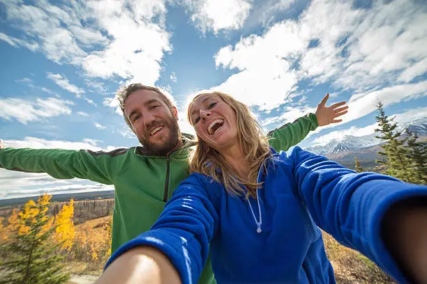 Young cheerful couple traveling in Canada takes a selfie portrait. Autumn season.