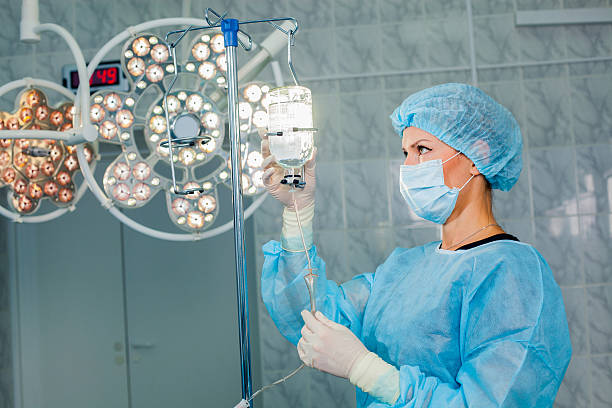 infirmière ajustant infusion bouteille avec fond de l'exploitation contre - iv drip chemotherapy drug bag intensive care unit photos et images de collection
