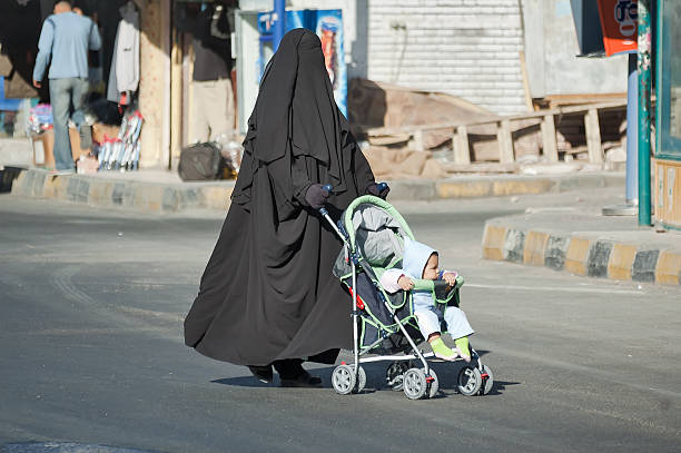 Arabic woman in hijab conducts carriage with child stock photo