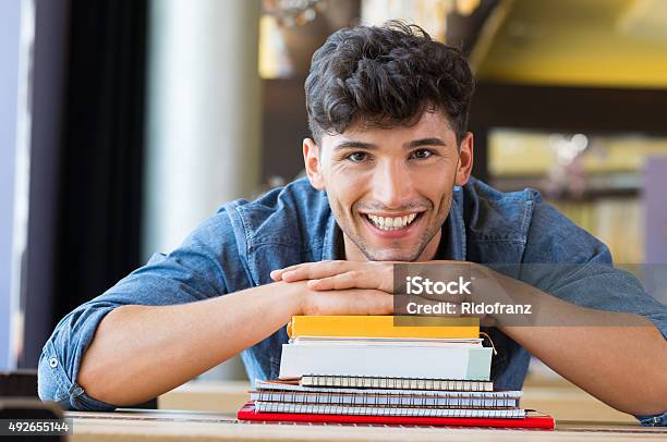 Young Man Leans On Stack Of Books Stock Photo - Download Image Now - University Student, Student, Studying