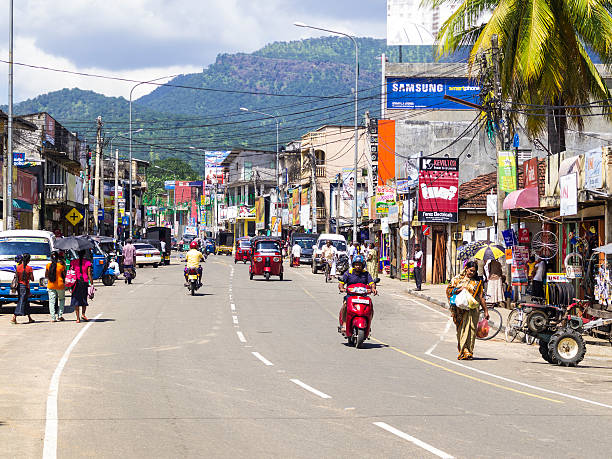 Detail from street in Wellawaya, central Sri Lanka Ginigathena, Sri Lanka - March 4, 2015: Frizz moment; detail from street in Ginigathena, with traffic and a lot of stores with commercial panels. On street are people walking, motor bikes and cars. In background are mountains and dynamic cloudy sky. sri lanka business stock pictures, royalty-free photos & images