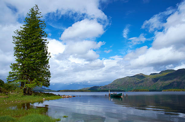 Early morning sunlight falls across the serene waters of Loch Maree, in Scotland's Northwestern Highlands.