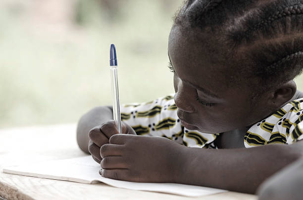 escrito y símbolo de aprendizaje: linda niña en edad escolar africano haciendo los deberes - african descent africa african culture classroom fotografías e imágenes de stock