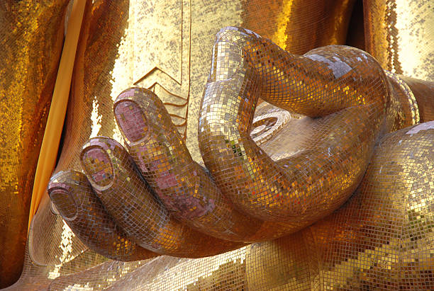 Gold coated buddha staue with rised hand. This position is called \