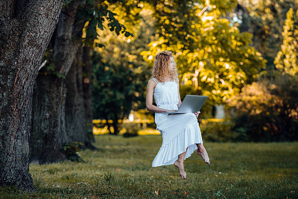 girl levitates with laptop beautiful girl levitates in nature with laptop levitation stock pictures, royalty-free photos & images