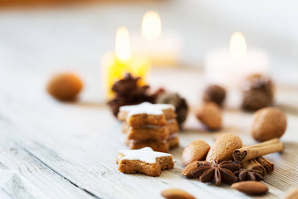 christmas cookies in star shape, spices like star anise and cinnamon, candles burning in background