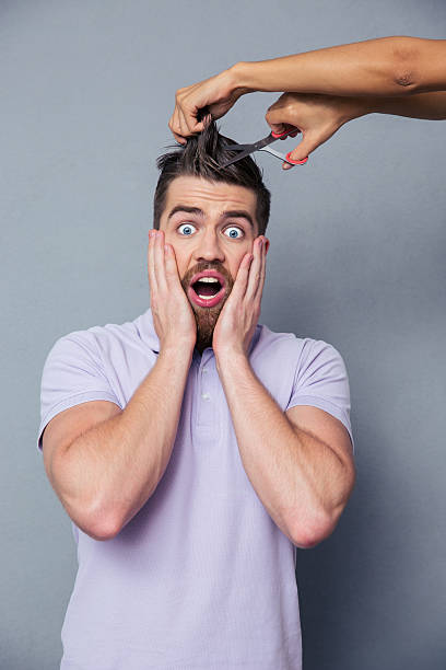 istock Man looking frightened while female hands cutting his hair 492673116