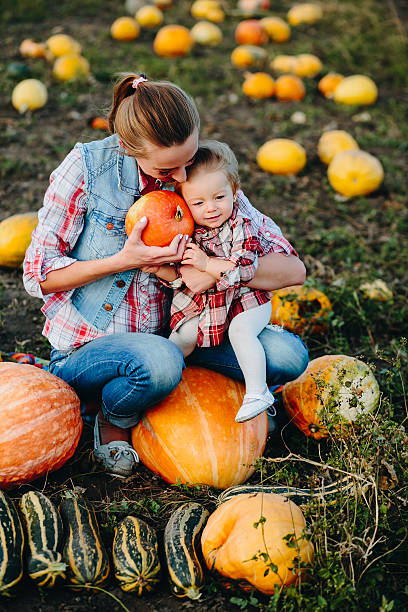 istock Mother and daughter sitting on pumpkins 492674590