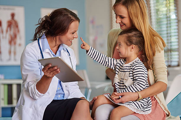 médico não é como um pouco assustador como ela parece - mother holding child pointing imagens e fotografias de stock