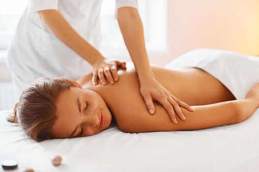 Spa treatment. Woman enjoying relaxing back massage in cosmetology spa centre. Body care, skin care, wellness, wellbeing, beauty treatment concept.
