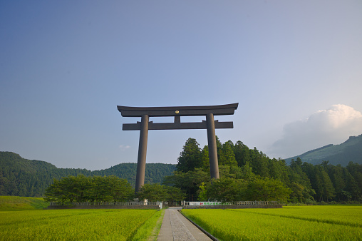 Hongu,Japan - August 4, 2015: The giant torii gate of Oyu no Hara closeby the Grand Hongu Taisha Shrine. Reference to the Hongu Taisha was first documented in the 9th century, which the establishment of the shrine must have preceded substantially. Due to floods in 1889, the shrine was moved from its original location at Oyu no Hara to its present site one kilometer away. In front of Oyu no Hara stands the biggest torii gate in the world, which, at 33 meters tall, dwarfs visitors passing under it