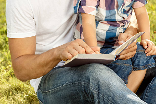 istock Father and son reading book in park 492679202