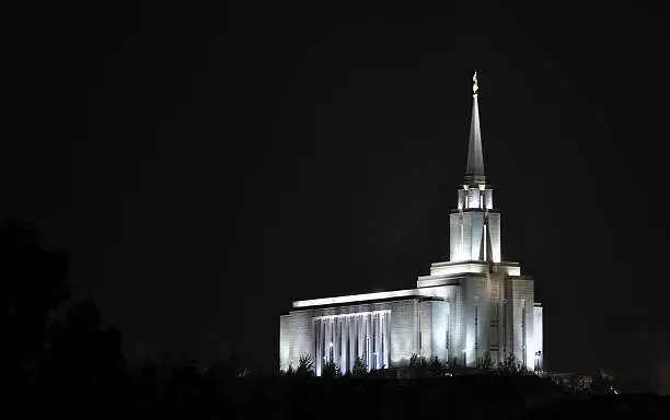 A night shot of the Oquirrh Mountain Temple of the Church of Jesus Christ of Latter-day Saints ("LDS" or aka Mormon), located in South Jordan, Utah.  The image shows the front (East) and side (South) of the temple.  A sculpture of the Angel Moroni sits atop the spire. The temple has been in operation since 2009. Mormons go to temples like this to be married for not only time but also eternity.