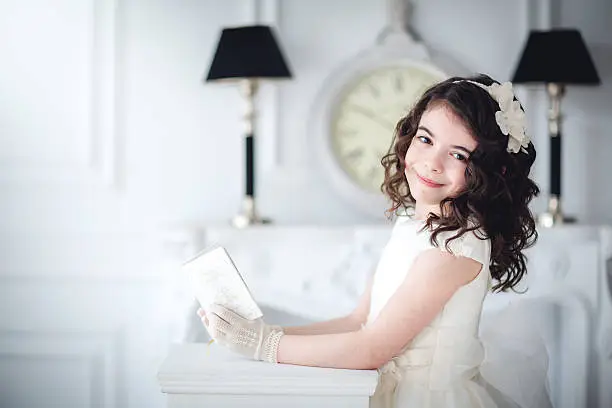 A girl with the book, Bible the hands in a palace with white background behind fireplace