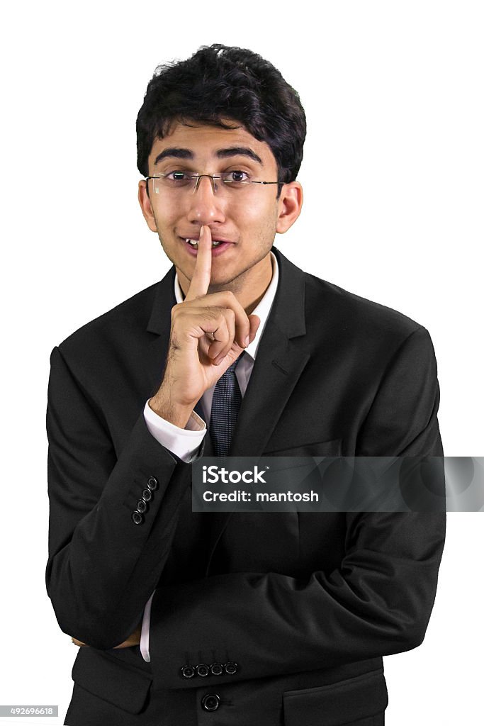 Shhhh! A smiling executive telling you to keep your silence with a finger to his lips. Culture of India Stock Photo