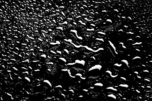 Drops of rain on a black rubber surface close-up.