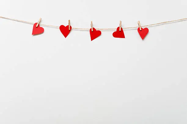 Red hearts with clothespins hanging on clothesline
