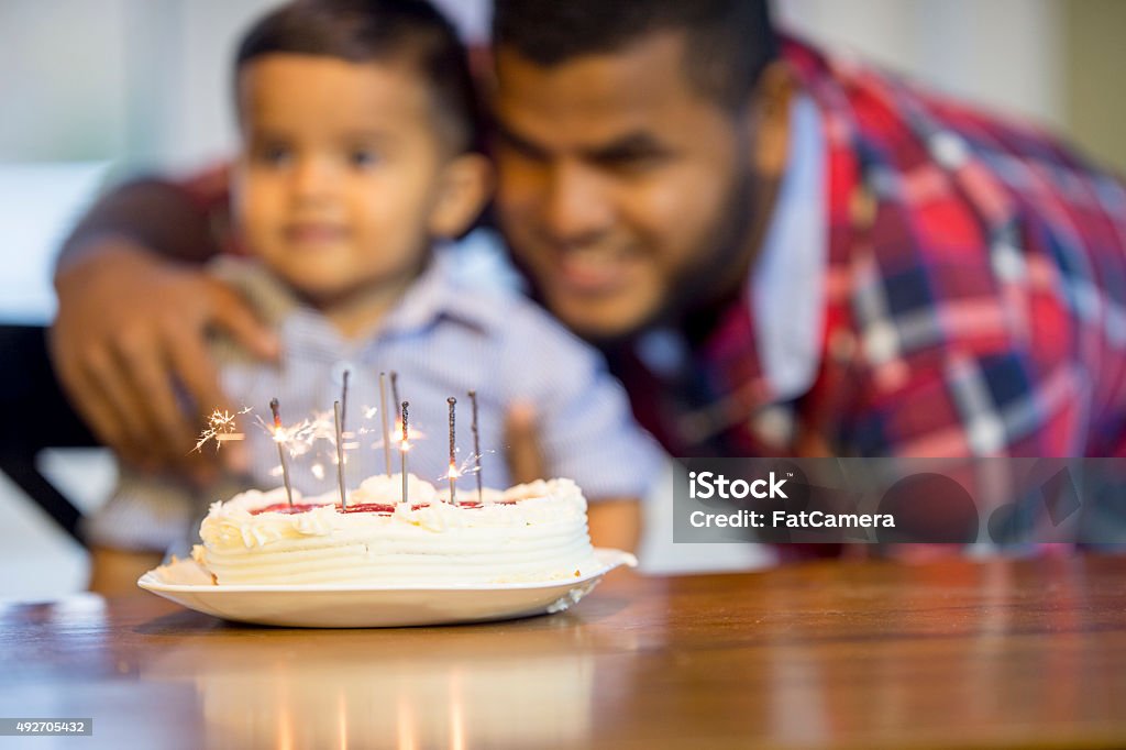 Sparkling Birthday Candles A little boy and his father are sitting together at the kitchen table on the child's first birthday. A cake is sitting on the table with sparkling candles burning. 12-23 Months Stock Photo