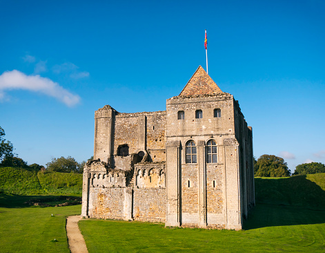 Castle Rising, Norfolk, England - September 26, 2015: Castle Rising castle keep and bailey on a bright sunny day in early autumn. The castle is one of the best known in England: it dates from the 12th century and is surrounded by huge earthworks. It was owned by Queen Isabella (The She-Wolf of France) and was where she remained under house arrest for her alleged part in the death of her husband, Edward II in 1327: Isabella died at Castle Rising in 1358. At the time she lived there, Castle Rising was extremely luxurious.
