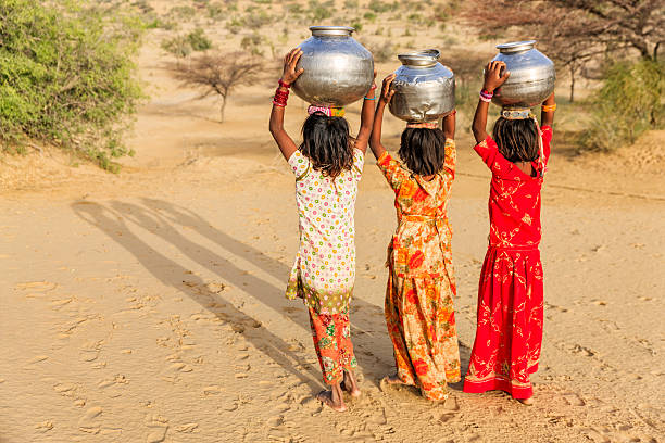 indische mädchen tragen von wasser auf den kopf gut - poverty india child little girls stock-fotos und bilder