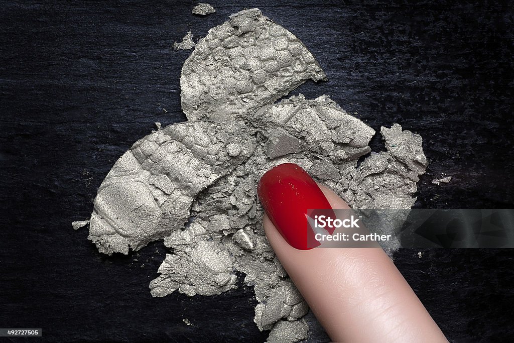Red Nail Polish and Mineral Silver Eye Shadow Finger woman with elegant red nail polish crushes a silver eyeshadow on a blackboard. Manicure and makeup concept Adult Stock Photo