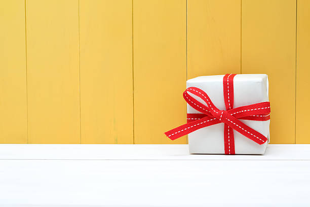 istock Cute white and red gift box on yellow background 492728652