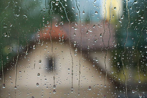 Rain drops on window with house and church in background stock photo