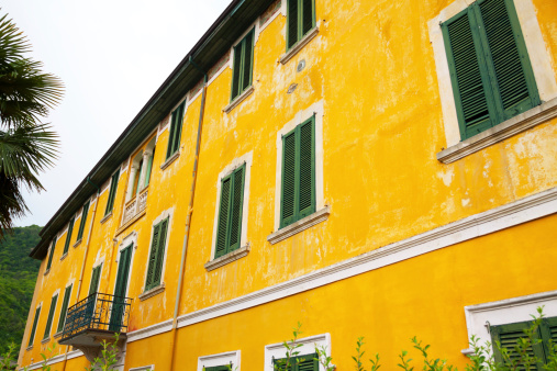 Abandoned house withyellow colored facade and green shutters in Lombardy, close to Lake Lugano.