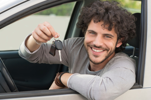 Portrait Of Young Happy Man Showing The Key Sitting In New Car