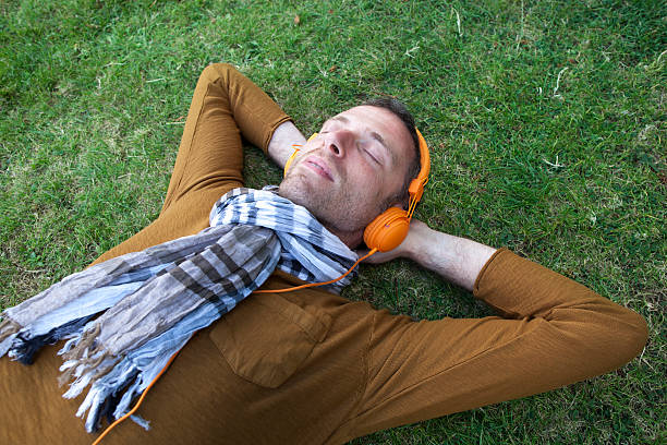 istock happy young man with headphones napping on grass 492735120