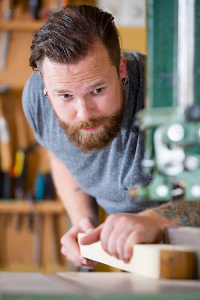 istock Craftsman using bandsaw for splitting wood plank in workshop 492735866