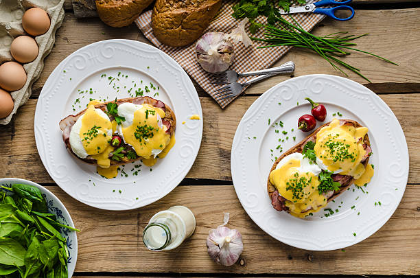 Eggs Benedict Eggs Benedict with little salad, milk and fresh herbs hollandaise sauce stock pictures, royalty-free photos & images