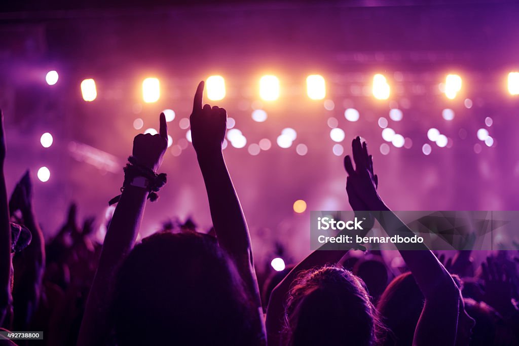 Put your hands up in the air! A crowd of people celebrating and partying with their hands in the air to an awesome Dj. High ISO grainy image. Lighting Equipment Stock Photo