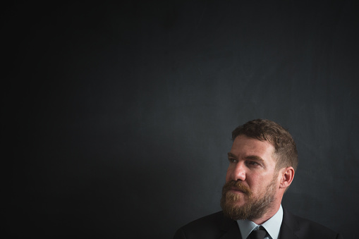 Handsome young man in formalwear looking at camera on blackboard.