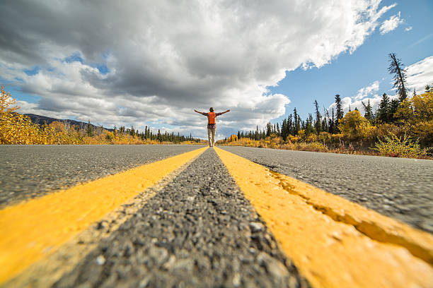 istock Distant woman standing on road arms outstretched 492752360